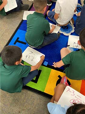 Students working through math problems on the floor in the classroom